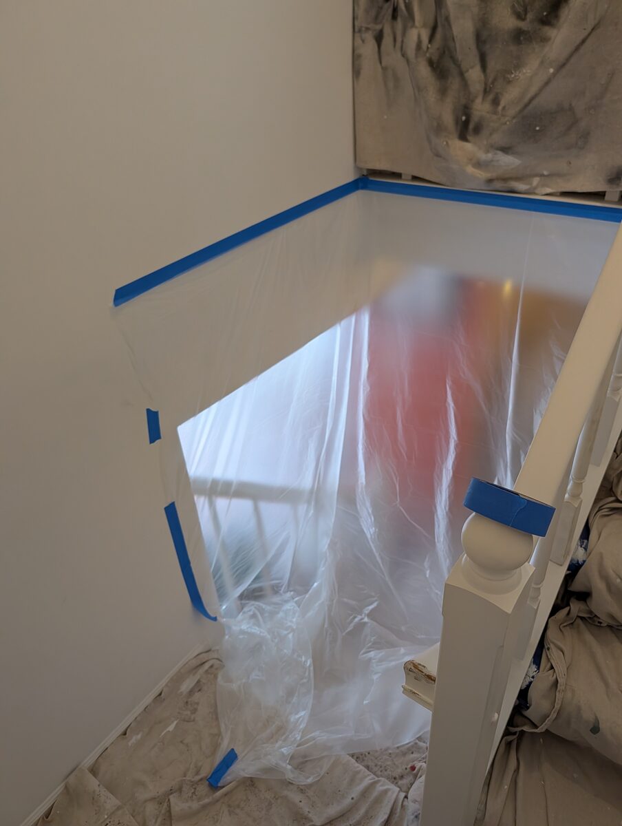 Plastic sheeting containment sealing off a stairwell before popcorn ceiling removal